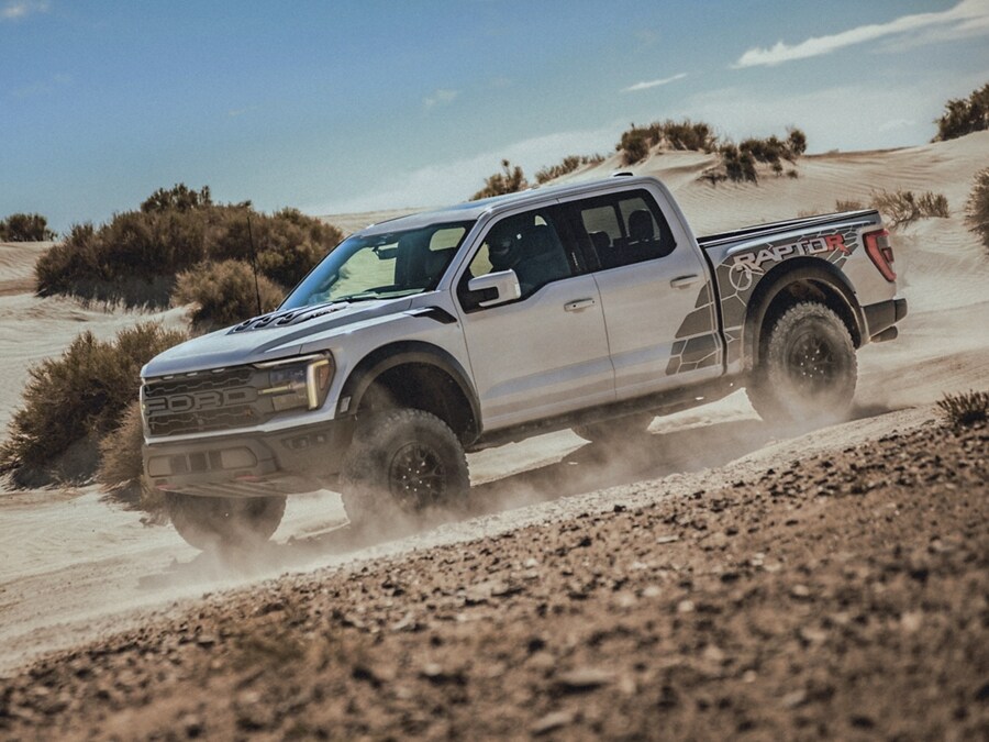 2024 Ford F-150® Raptor being driven off-road in the desert kicking up dust