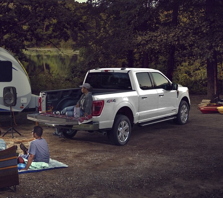 Family at a campground watching a projected movie on the side of a camper powered by the Pro Power Onboard feature