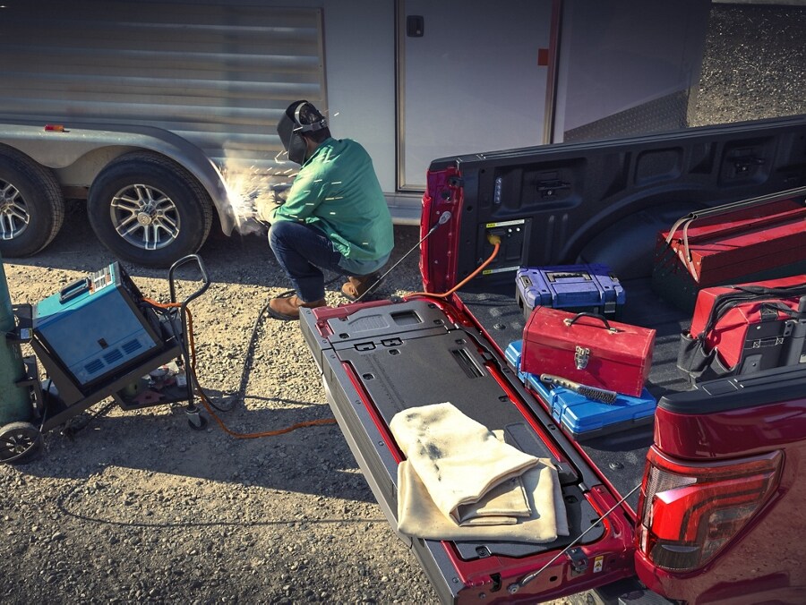 Person using a TIG welder that's plugged into the Pro Power Onboard feature located in the truck bed
