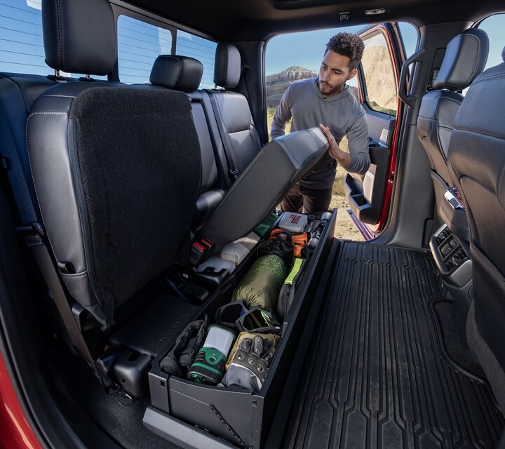 Man flipping up the lockable seat showing items in the storage bin