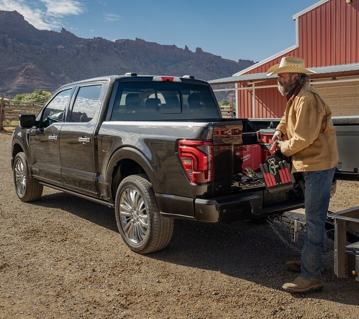 Man loading items into the truck bed with the Pro-Access Tailgate open