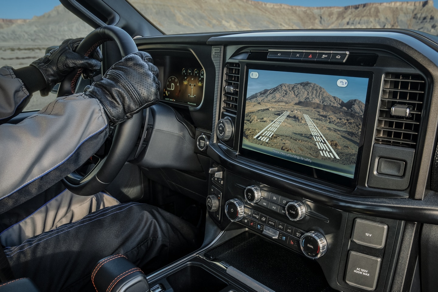 Person driving Ford F-150 while navigation displays the surround areas around the truck on screen using the sensors and exterior cameras
