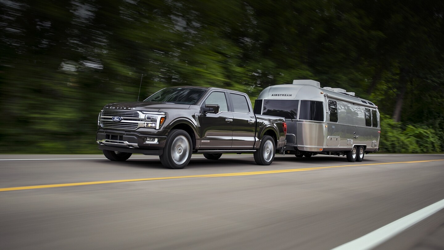 2024 Ford F-150 Platinum towing silver Airstream on highway. 