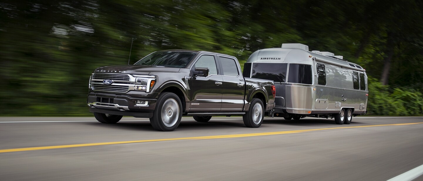 A 2024 Ford F-150® pickup in Agate Black pulling an Airstream Camper