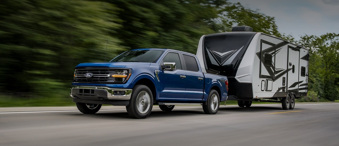 2025 Ford F-150® XLT driving down a paved road with a camper attached