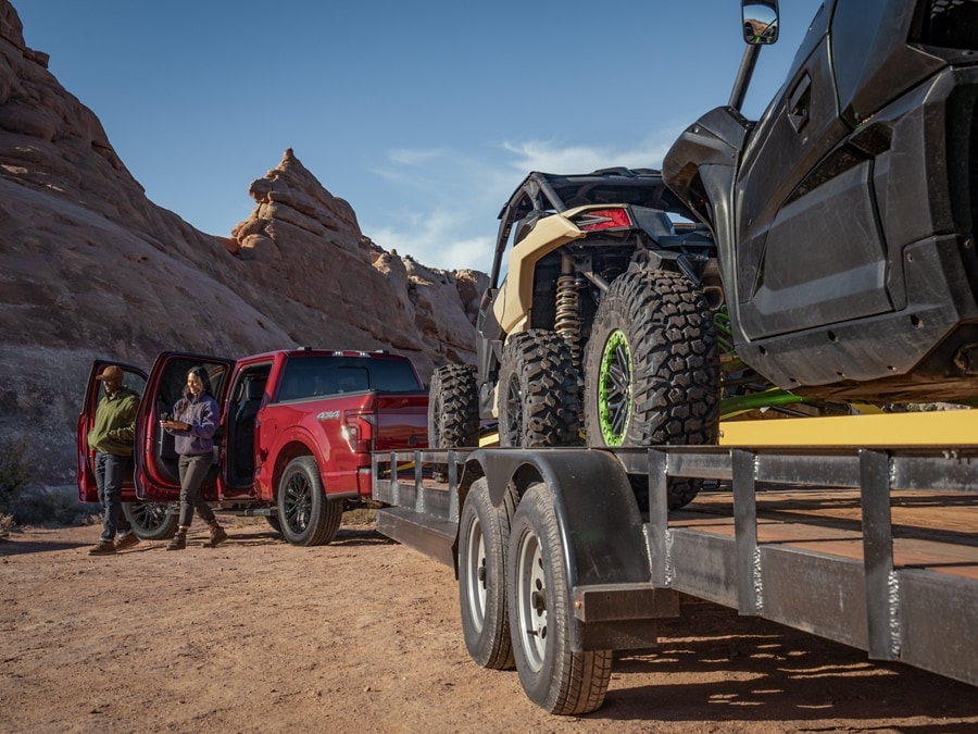 Ford Red F-150 pulling a trailer full of ATVs on sand