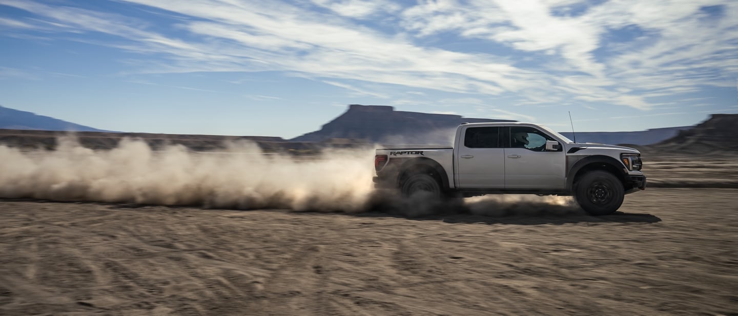 2024 Ford Raptor speeding through a heavily sandy desert