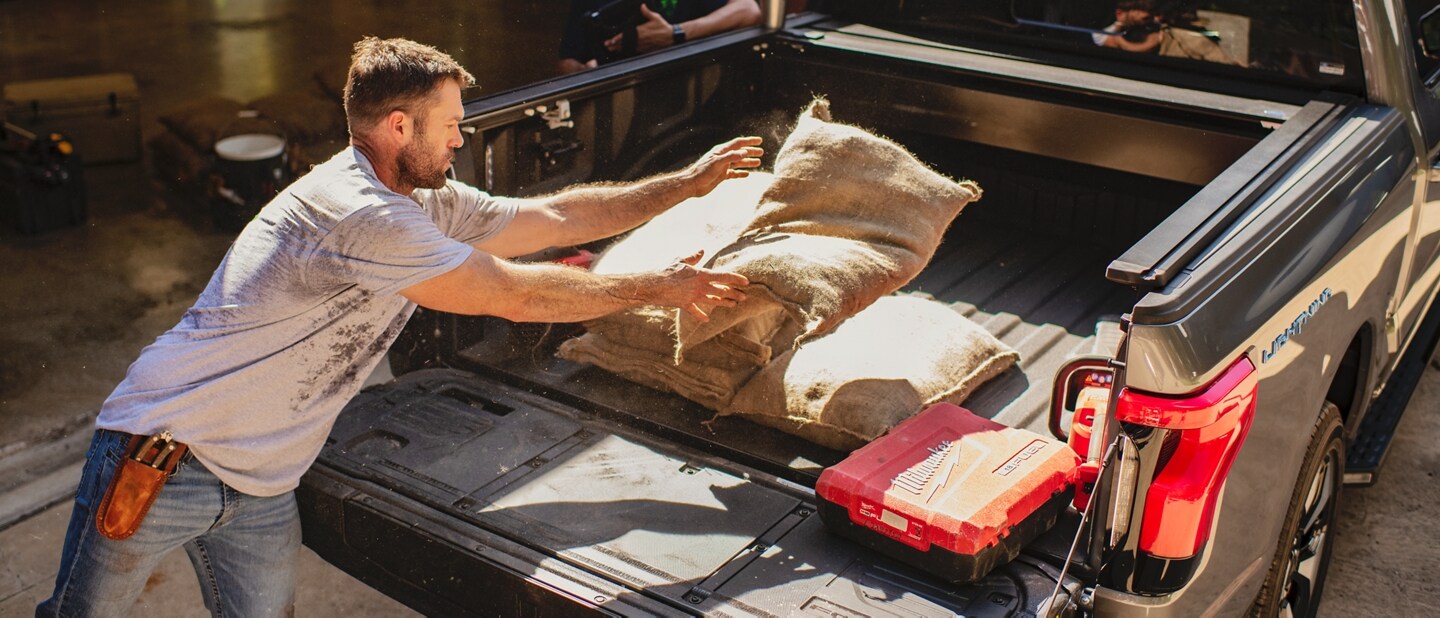 Man loading bags into the back of the 2023 Ford F-150 Lightning®