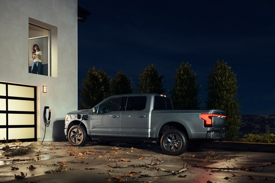Woman in window of house while waiting for 2023 Ford F-150 Lightning to charge