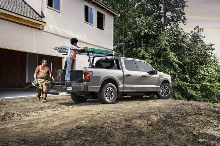 Man loading a ladder on a rack attached to a 2023 Ford F-150 Lightning®