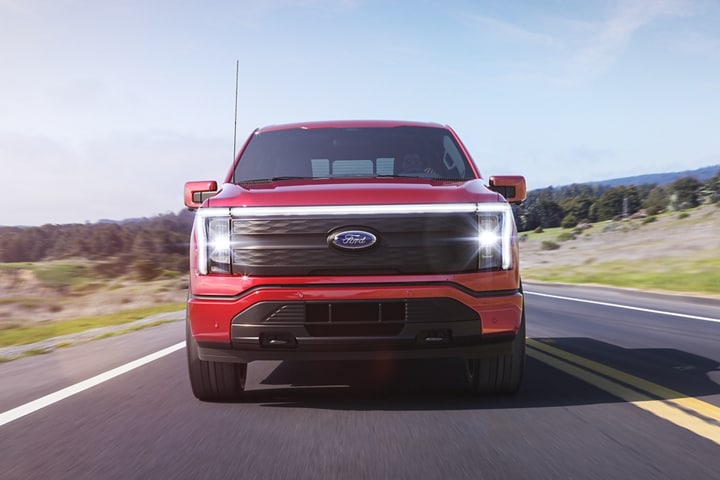 Straight-on shot of a 2023 Ford F-150 Lightning® being driven down oceanside road