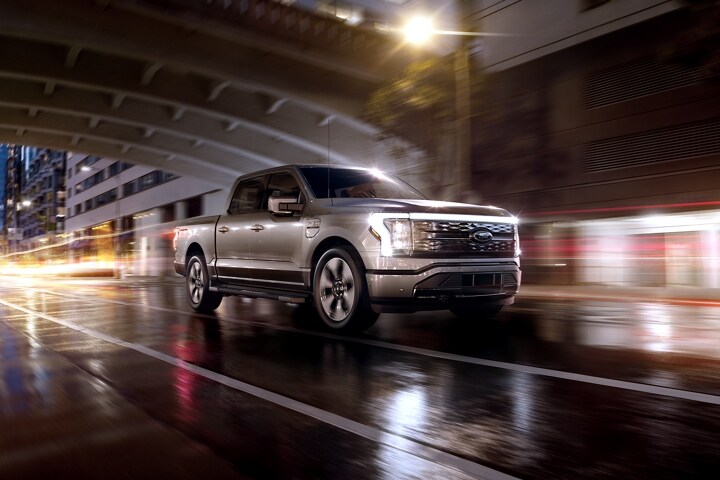 A 2023 Ford F-150 Lightning® being driven on city street at night