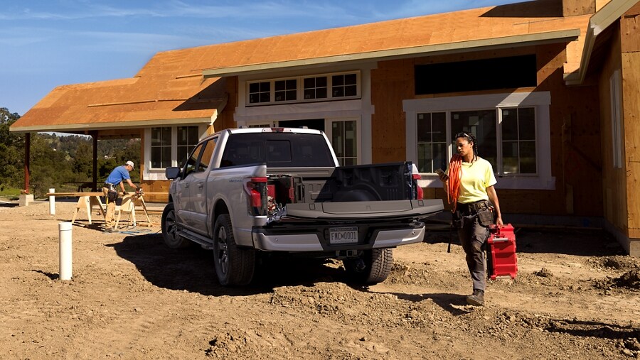 Construction worker carrying heavy toolbox to open bed