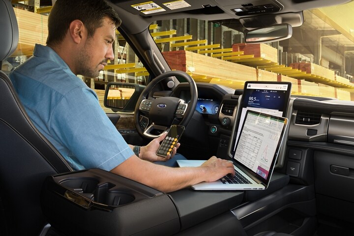 Interior of a 2023 Ford F-150 Lightning® with man working on his computer on the work surface