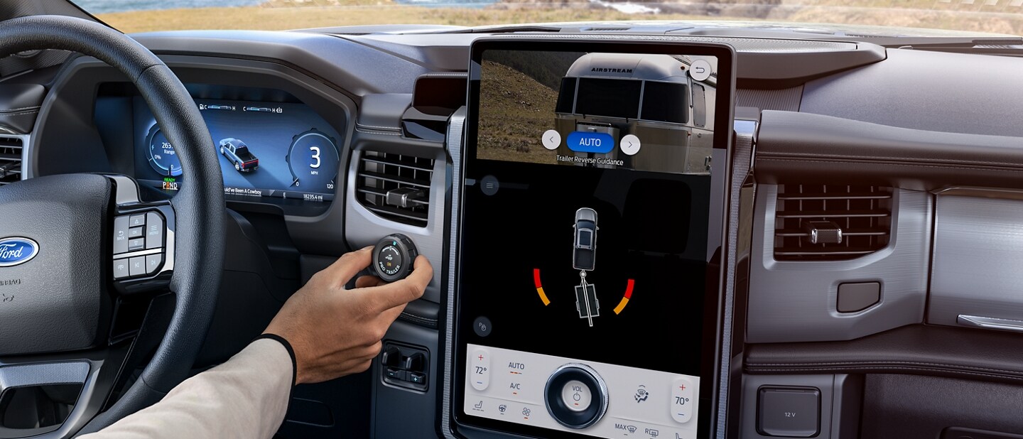 Man turning the knob on the dash as he watches the image on the touchscreen