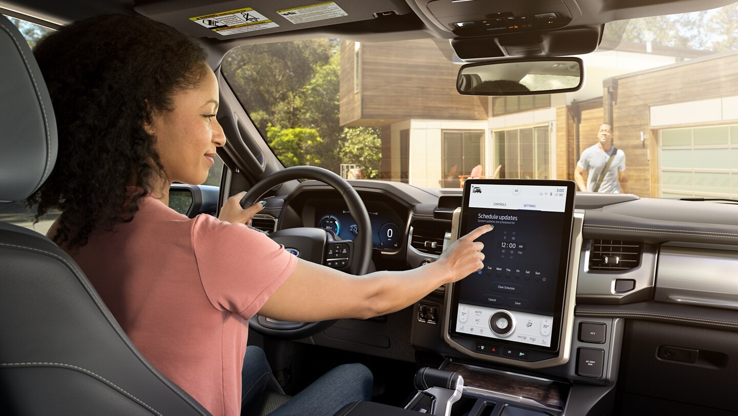 Interior shot as woman driver interacts with touchscreen