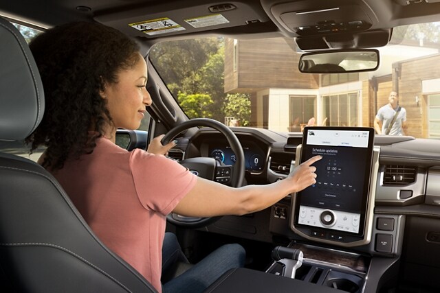 Interior shot as woman driver interacts with touchscreen
