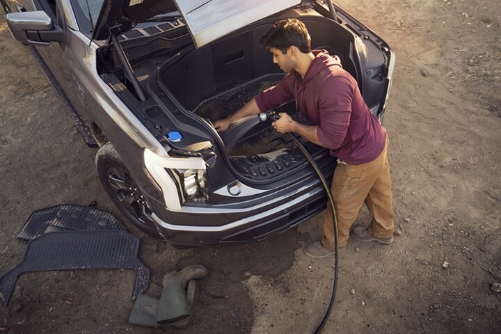 A 2023 Ford F-150 Lightning® as a man washes out the open Mega Power Frunk