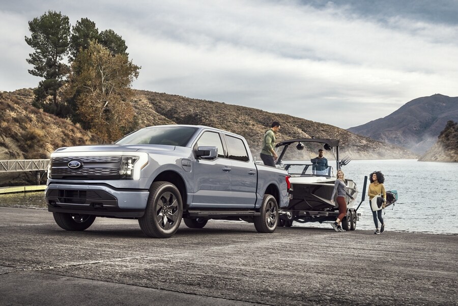 A 2023 Ford F-150 Lightning backing a boat into the water at a public launch