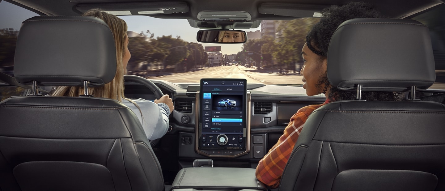 Interior photo from rear seat of the front dash as two women sit in front seats