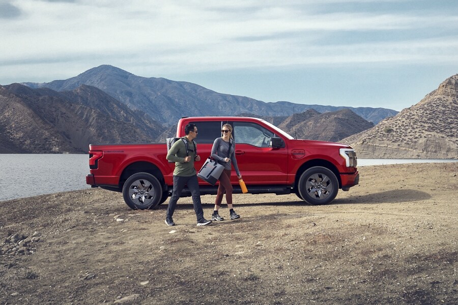 A 2023 Ford F-150 Lightning® parked at edge of mountain lake, mountains in background