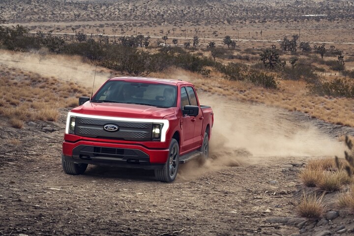 A 2023 Ford F-150 Lightning® driving through the desert mountains in background