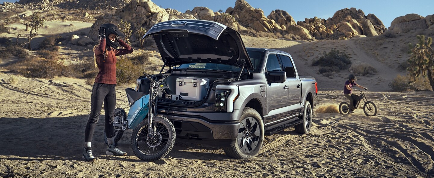 Cyclist in the desert unloading his gear from the frunk of a 2023 Ford F-150 Lightning
