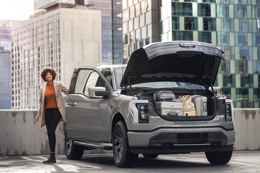 A 2023 Ford F-150 Lightning™ parked on rooftop parking, Mega Power Frunk open and filled
