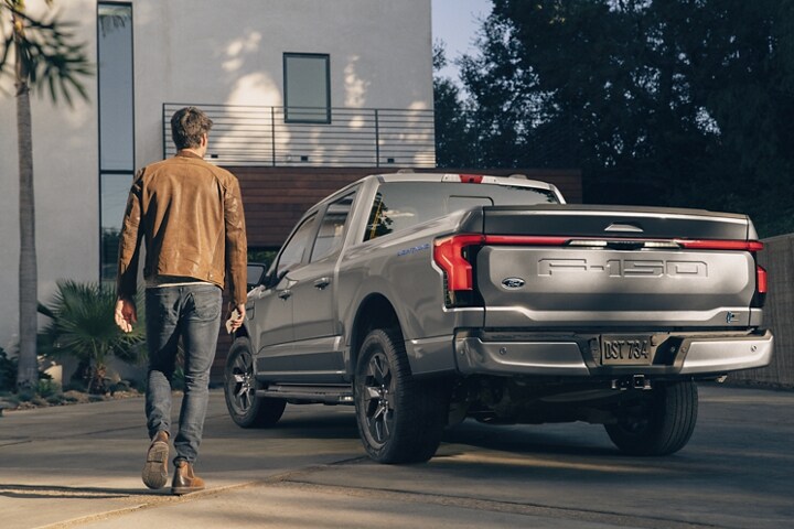 Guy walking towards his 2023 Ford F-150 Lightning® parked in driveway