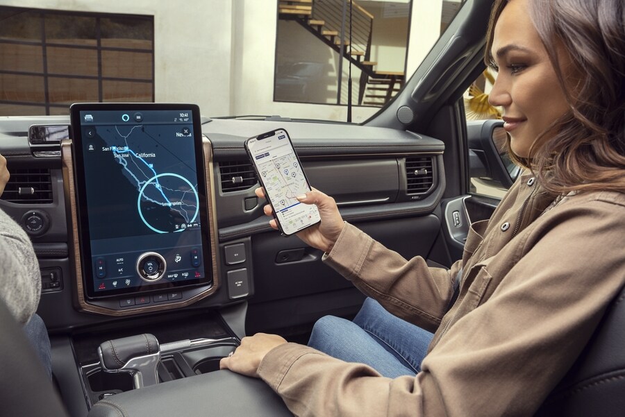 Interior of an 2023 Ford F-150 Lightning shows woman passenger connecting her phone to the display screen