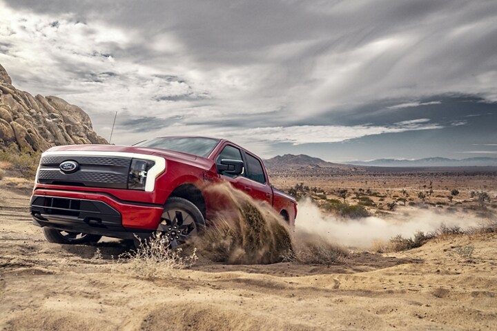 A 2023 Ford F-150 Lightning® being driven on a forested trail