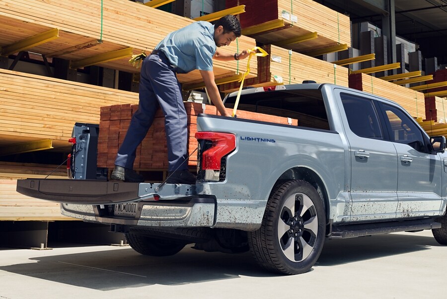 A 2023 Ford F-150 Lightning in a lumber yard being loaded with a heavy pallet of boards