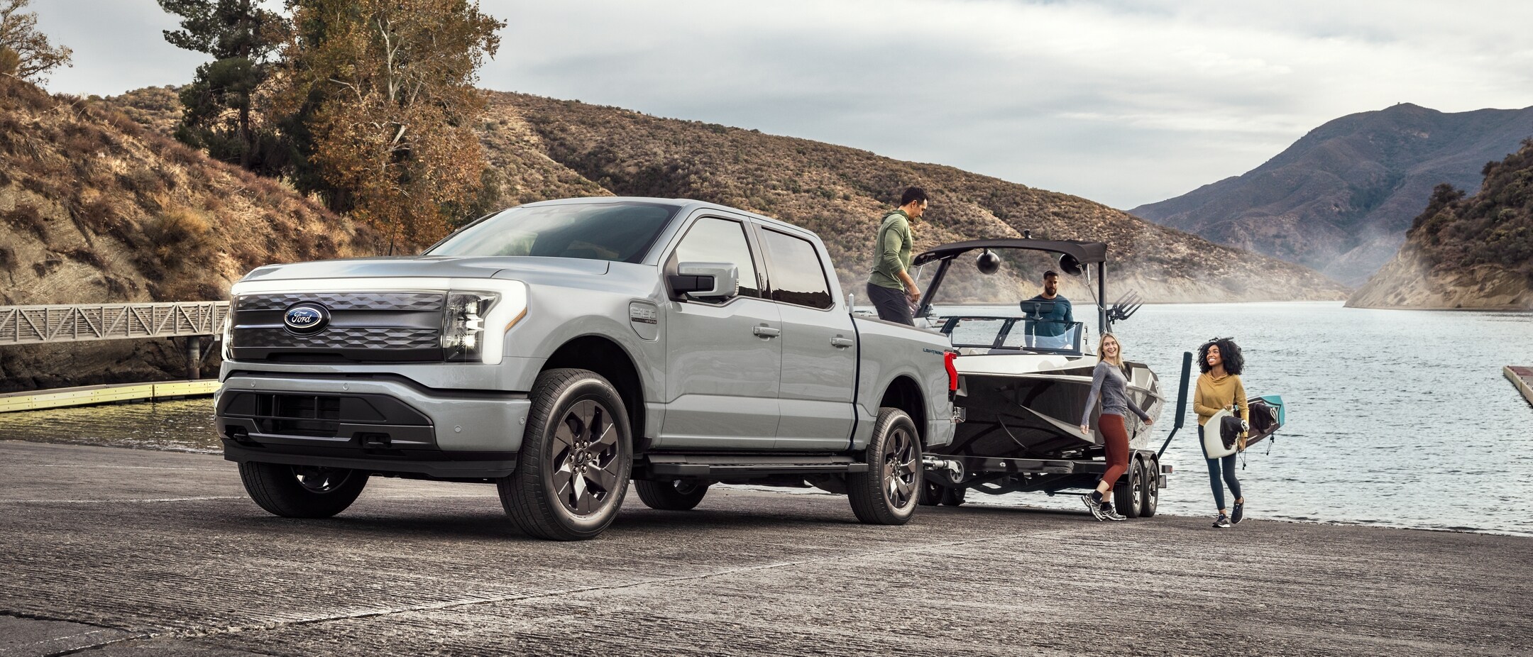 Silver ford f-150 lightning being used to tow a speedboat out of the water