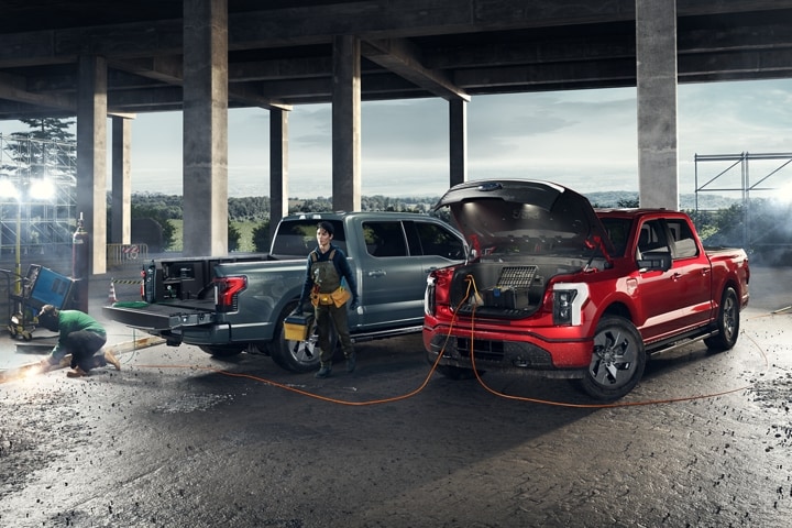 Two 2023 Ford F-150 Lightnings® at a work site powering tools like welder, saw etc