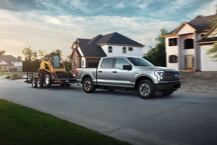 2023 Ford F-150® Lightning® pulling a tractor down a suburban street