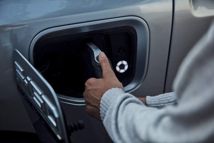 Woman plugging in her 2023 Ford F-150 Lightning at a public charging station