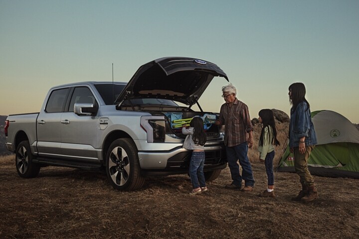 Una familia desempacando el equipo de campamento de la cajuela de la Ford F-150 Lightning® 2023