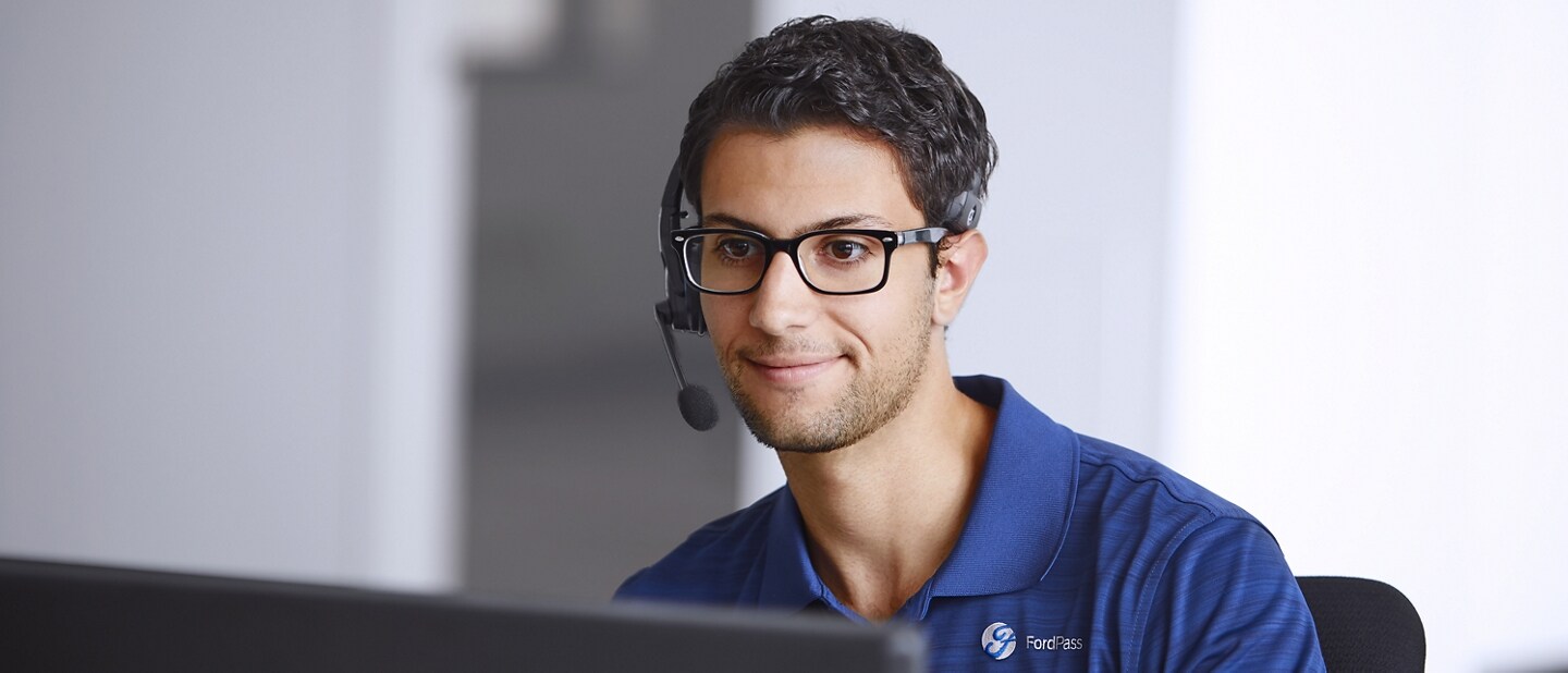 Person wearing a microphone headset sits in front of a computer screen