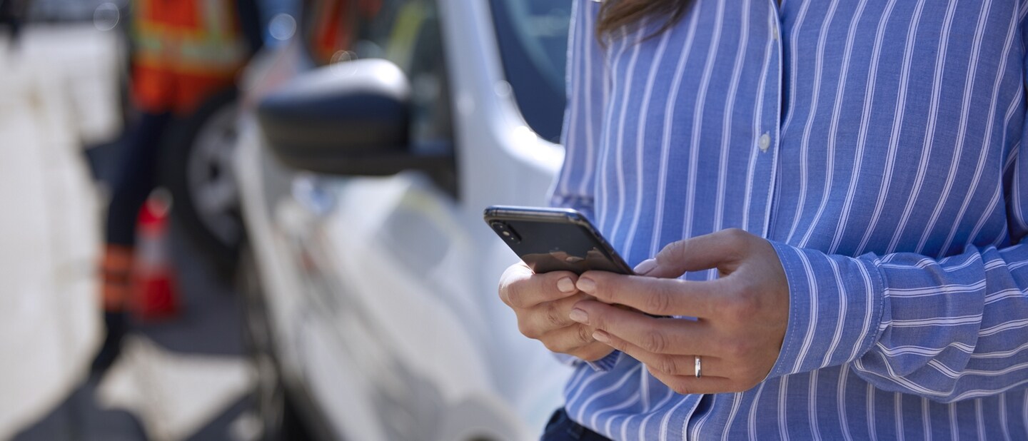 Person uses smartphone while a technician repairs a tire