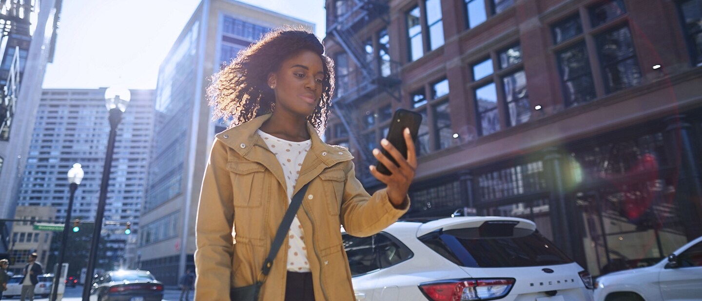 Person walking on a city sidewalk using a smartphone
