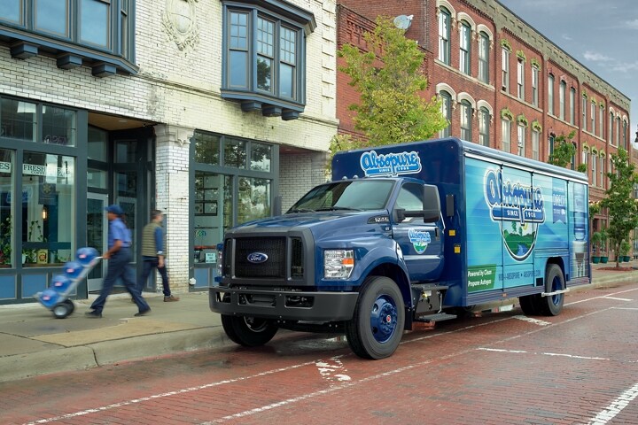 Worker unloading water from 2023 Ford F-750 Regular Cab with beverage truck upfit and Absopure custom design