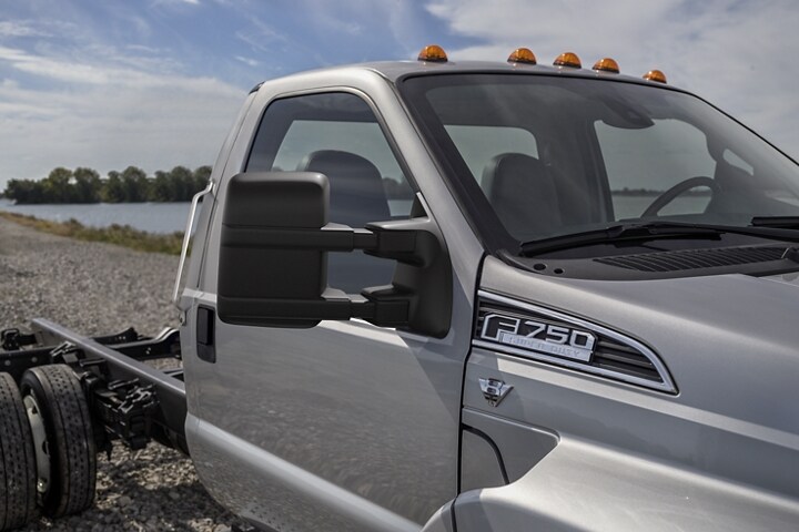 Primer plano de los espejos de una Ford F-750 Regular Cab 2024 en Ingot Silver estacionada cerca del agua