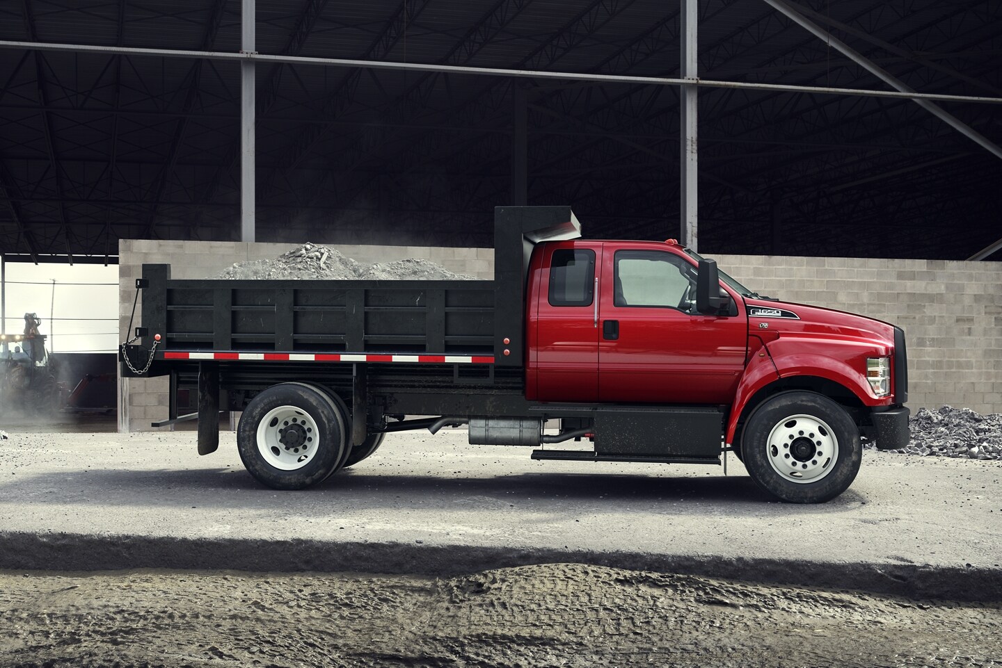 2024 Ford F-650 Red SuperCab Dump Truck parked at a construction site.