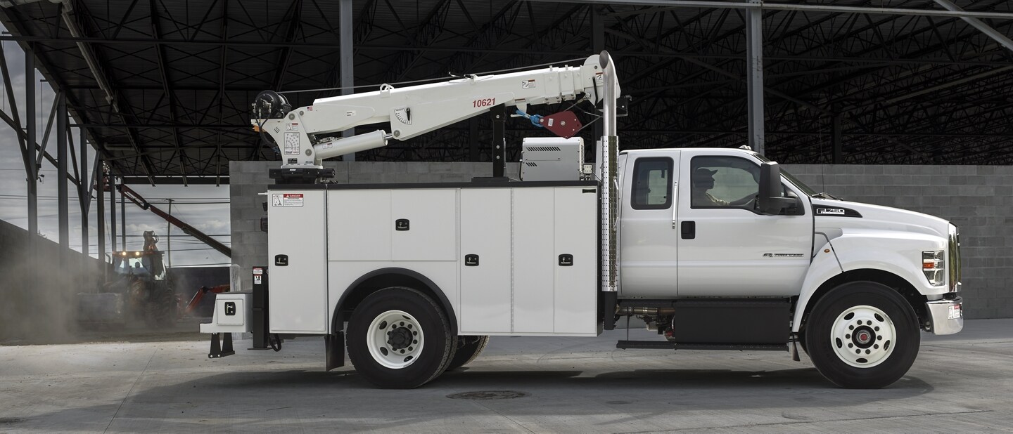 Una Ford F-750 SuperCab 2024 en Oxford White con mejora mecánica estacionada cerca de un sitio de construcción