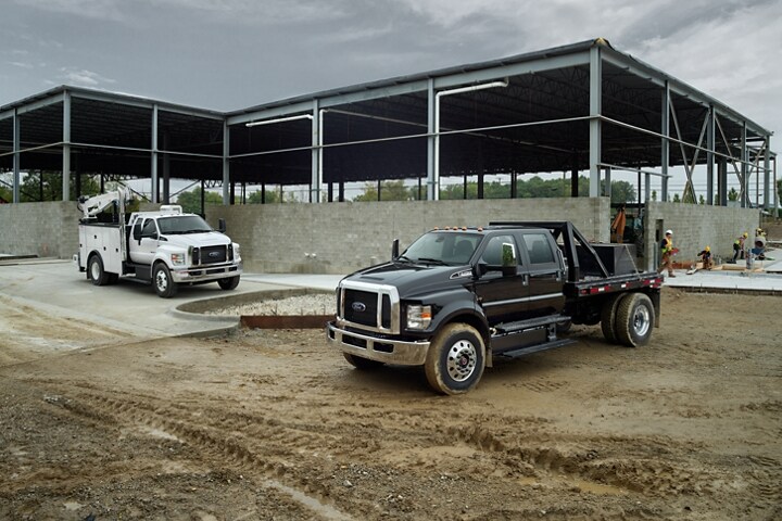 2024 Ford F-750 SuperCab with upfit in Oxford White and 2024 Ford F-750 Crew Cab in Agate Black with upfit at work site