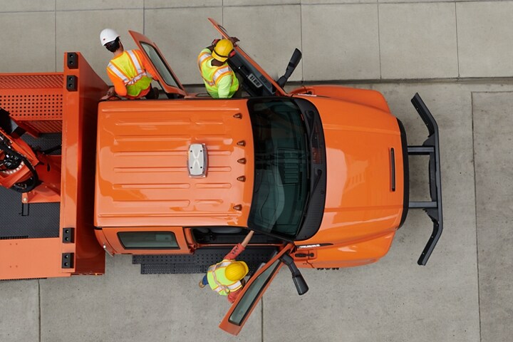 Vista aérea de unos trabajadores saliendo de una Ford F-750 Crew Cab 2024 con mejora de plataforma elevadora en Tangier Orange