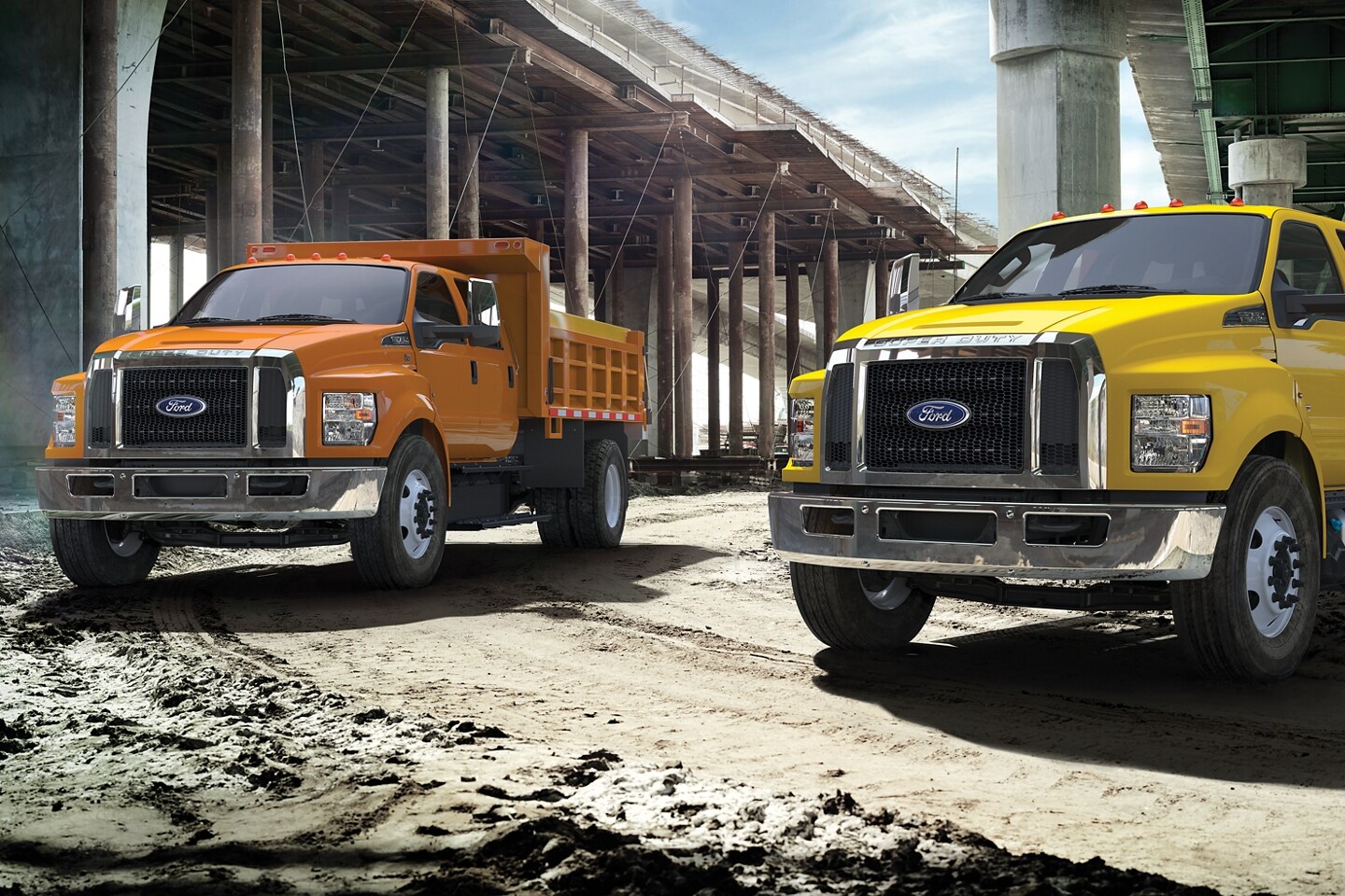 Orange 2024 F-750 & Yellow 2024 F-750 Ford Dump Trucks under a unfinished highway bridge