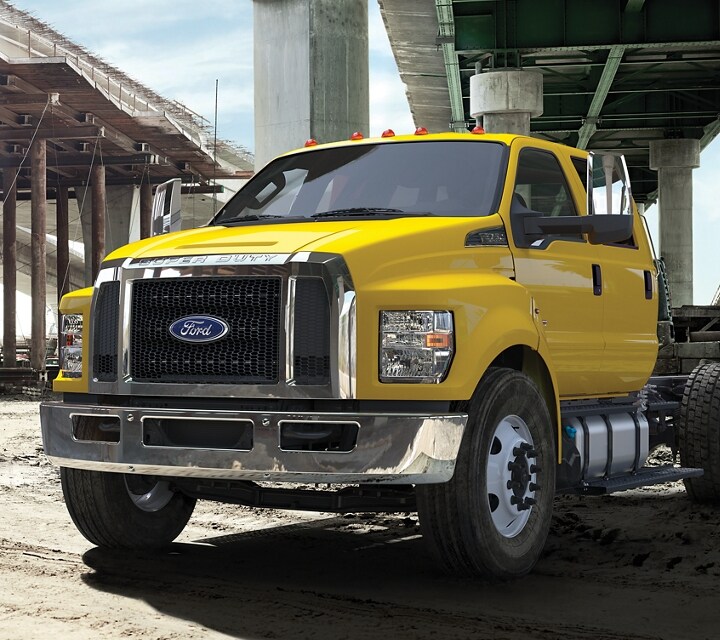2024 Ford F-750 models with dump truck upfits parked alongside one another near overpass