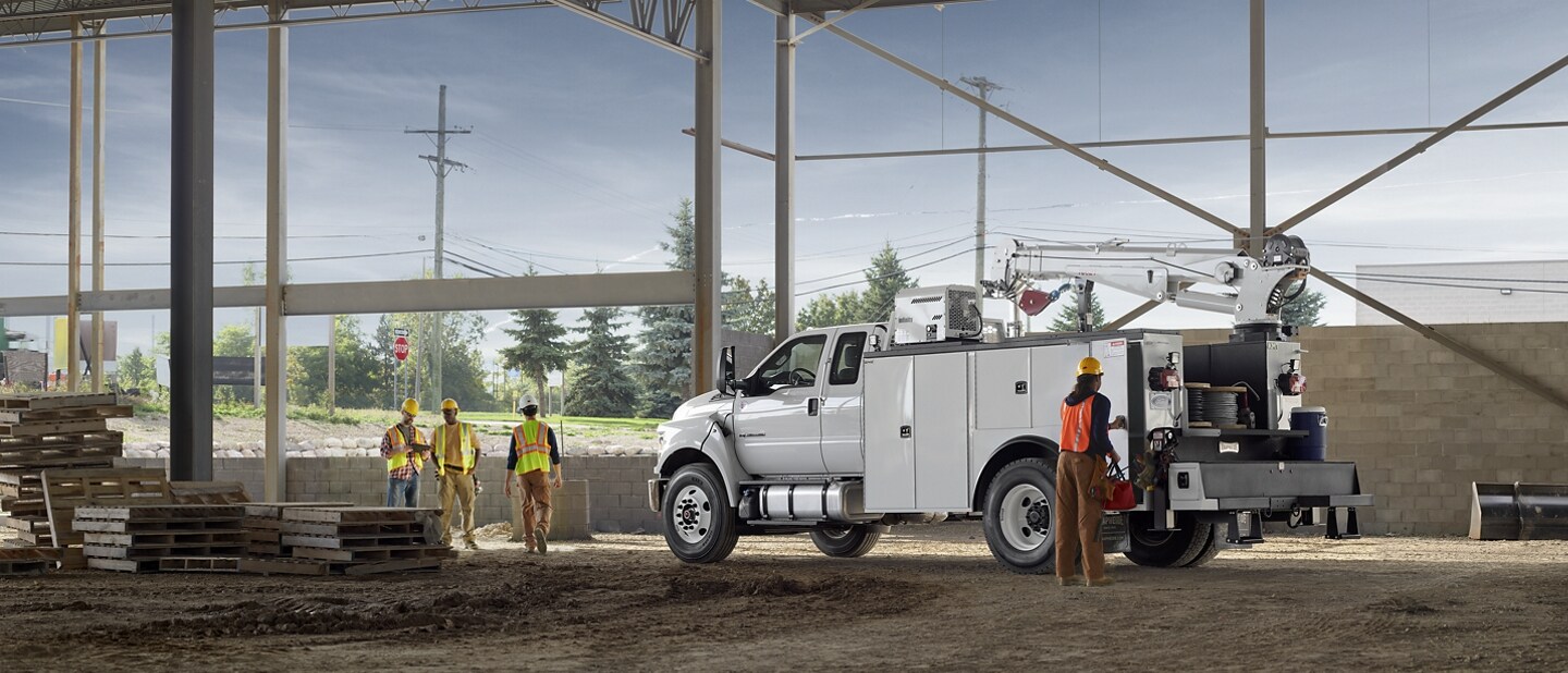 Workers near 2024 Ford F-750 SuperCab in Oxford White with mechanic truck upfit parked at construction site