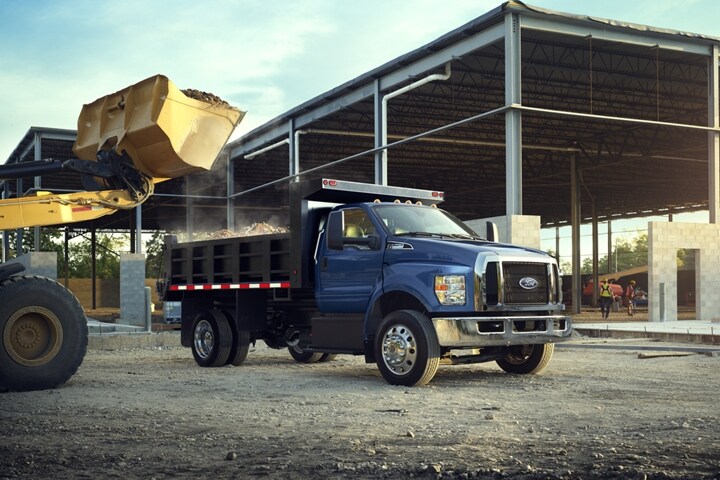 Un cargador delantero volcando tierra en la mejora de volquete de una Ford F-750 Regular Cab 2024 en Blue Jeans